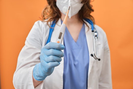 A female doctor holds an electronic digital thermometer in her hand. Medical instrument for...