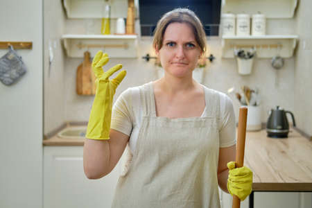 Angry woman glares at the camera while cleaning in the home kitchenの写真素材