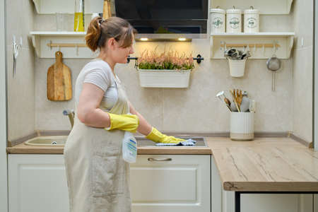 A woman washes an electric induction cooker with a rag when cleaning a home kitchenの写真素材