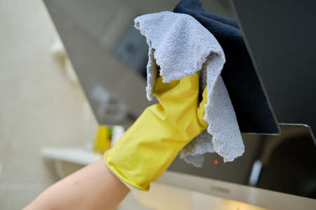 Woman washing with a rag an electric cleaning hood at home kitchenの写真素材