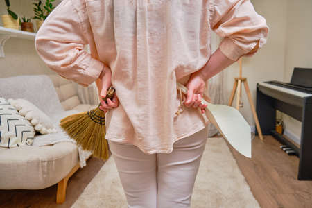 A woman with a broom and a dustpan is preparing for cleaning in the home living roomの写真素材