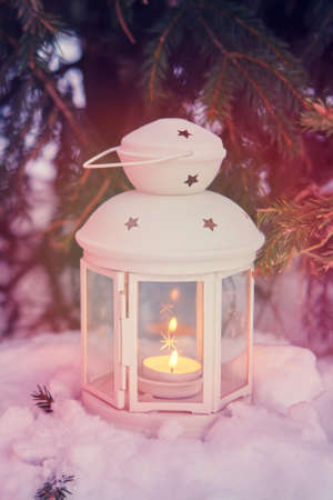 Lantern with a candle inside on background of a winter forestの写真素材