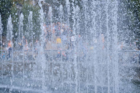 Blurred background of water fountain with jets of water and people, copy spaceの写真素材