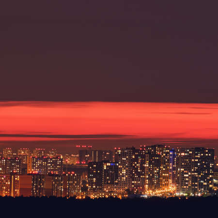 Night city lights at dusk sunset, red sky over housesの写真素材