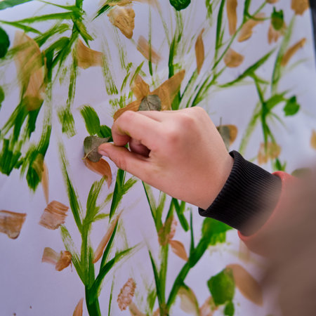 The child is learning to paint with paints on canvas, easel with paper. Boy artist paints nature
