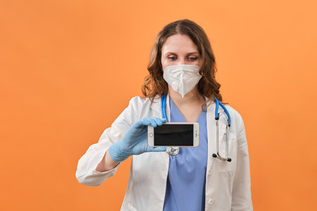 Doctor with a phone in her hands, copy space. Concept of remote care for patients with , helps patients through the Internet - Moscow, Russia, September 16, 2021のeditorial素材
