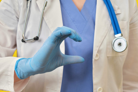 Hand nurse in the shape of a helf heart. Doctor in protective pink gloves and medical uniform, close-up.の写真素材