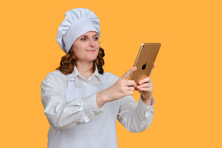 Happy woman with ipad apple tablet on yellow studio background, copy space - Moscow, Russia, October 20, 2021のeditorial素材
