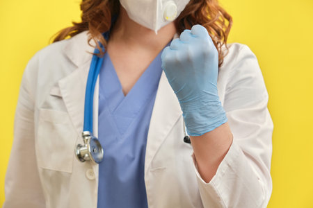 Hands of the doctor menacingly shows a fist. Close-up of a doctor in protective gloves and a medical...