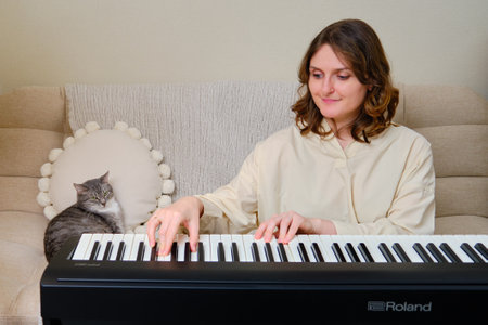 Woman musician playing electronic piano Roland at home on sofa in living room - Moscow, Russia, October 28, 2021のeditorial素材