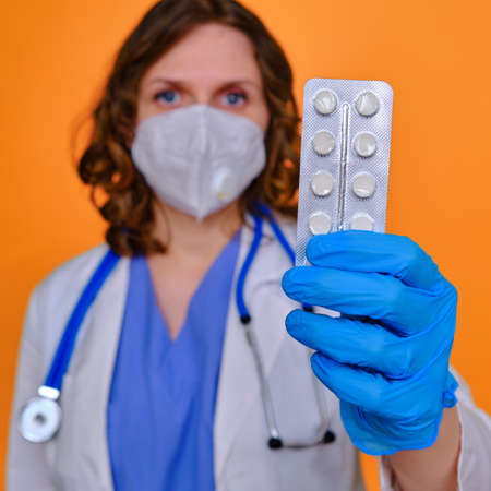 A female doctor holds a package of pills, studio backgroundの写真素材