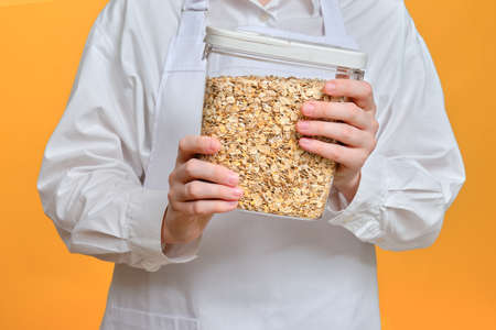 Man chef with container with cereal for porridge in hand on studio backgroundの写真素材