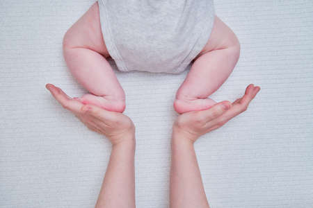 Mom female hands teach the infant baby toddler to crawlの写真素材