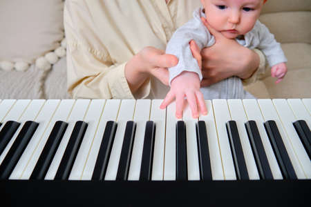 Woman musician with child teaches music on electronic piano at homeの写真素材