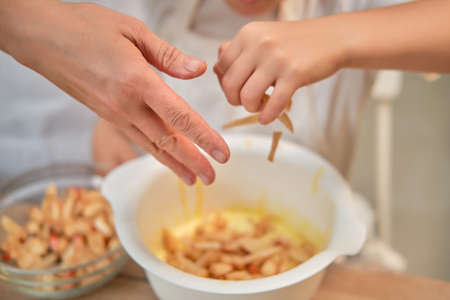 Mother and son cooking apple pie in the home kitchen. A woman and a boy in chef hats and aprons cook with pastriesの写真素材
