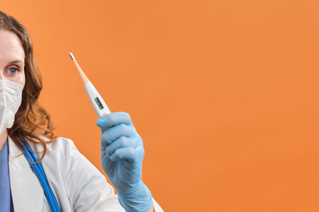 A female doctor holds an electronic digital thermometer in her hand. Medical instrument for...