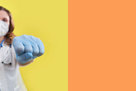 A doctor in medical gloves punches the virus, close-up. Concept of ending the coronavirus pandemic and lifting the quarantineの写真素材