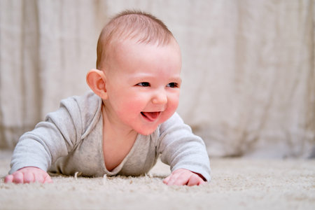 Happy infant baby is playing lying on a mat
