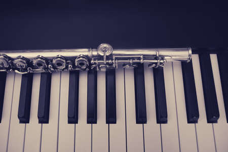 A large concert transverse flute lies on the piano keysの写真素材