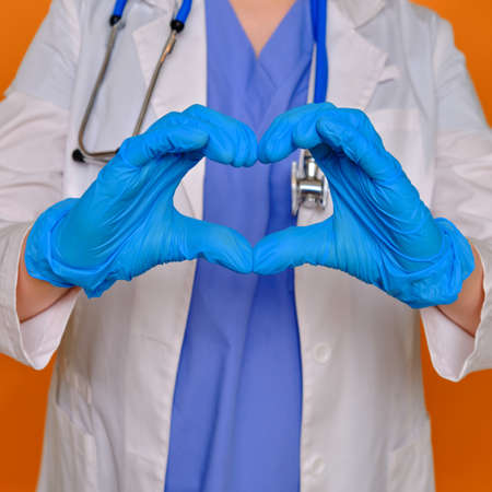 Concept of stay home, hands folded in the shape of a heart. Doctor in protective gloves and medical uniform, close-up.の写真素材