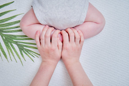 Woman mother helps to crawl infant baby by pushing off from palms of hands with feet