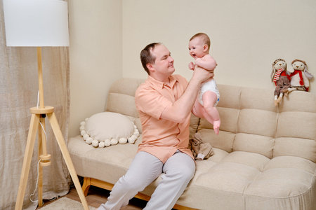 A man father and a boy son play together on the sofa in the home living room