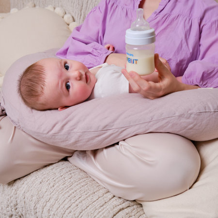 A mother woman feeds an infant baby formula from a Philips Avent bottle - Moscow, Russia, December 12, 2021のeditorial素材