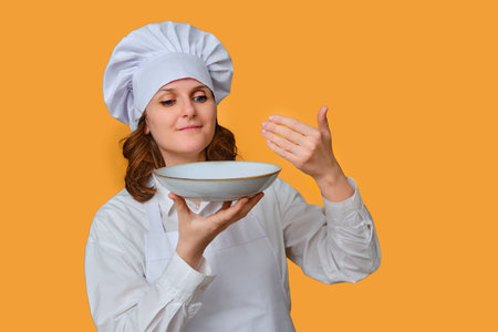 Happy woman sniffing the smell of food in a plate on a studio background, copy space