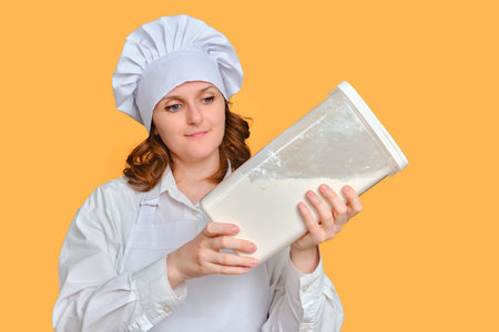 Smiling woman chef with large container of flour in hands on studio background, copy space