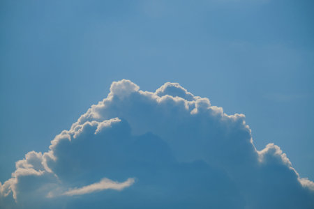 Sunset against a blue sky with a large white cloud, copy space