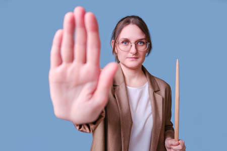 Woman teacher with stop hand gesture on studio blue background, copy spaceの写真素材