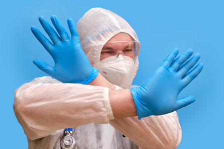 Man doctor medic in a protective suit uniform with goggles and face mask on a studio blue...