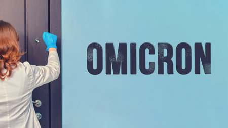 Woman doctor knocks on the door of the apartment with an inscription with a new version of Omicron covidの写真素材