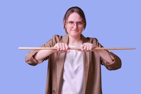 Stressful woman teacher with pointer on studio blue background, copy space