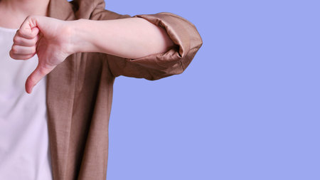 Woman teacher with thumb down gesture on studio blue background, banner copy spaceの写真素材
