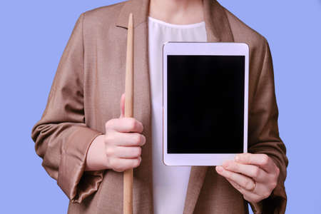 Woman teacher with tablet for online lesson on studio blue background, copy spaceの写真素材