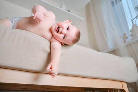 Infant baby falls off the sofa in the home living room. Toddler kid gets off the bed. Problems with the safety of children without parental supervisionの写真素材