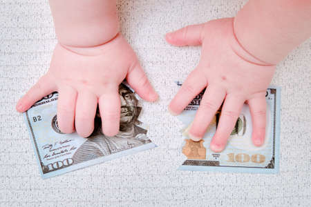Baby hand and torn money in ?? dollars, close up. Children fingers and an object on a white backgroundの写真素材