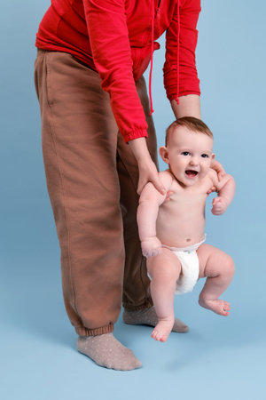 Mom teaches the child to stand on his feet and walk, baby boy on a blue studio background