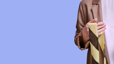 Woman teacher holds a yellow and black tape on a studio blue background, banner copy spaceの写真素材