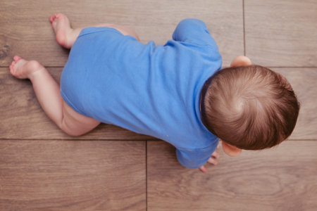 Happy baby toddler crawls on a wooden laminate. Funny child on the parquet in the home living room,...