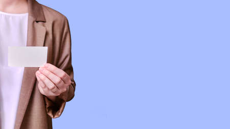 Woman teacher holding business card on studio blue background, banner copy spaceの写真素材