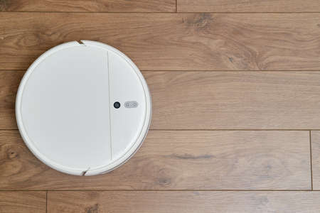 White robot vacuum cleaner on wooden parquet, close-upの写真素材