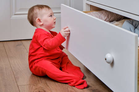 Danger for the baby to pinch the hand of the cabinet door or chest of drawers. Protect children from home furniture, kids safetyの写真素材