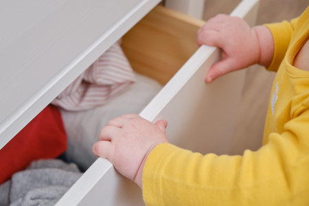 Danger for the baby to pinch the hand of the cabinet door or chest of drawers. Protect children from home furniture, kids safetyの写真素材