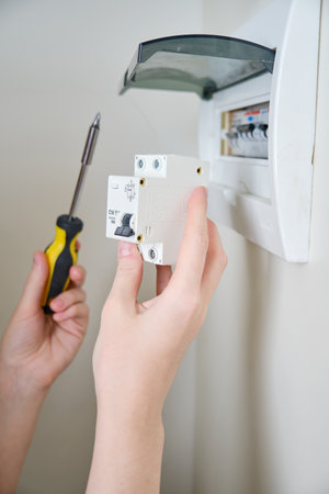 A woman changes an automatic fuse in a home electrical panel. Self repair and replacement of electricity equipment in the apartment, diyの写真素材