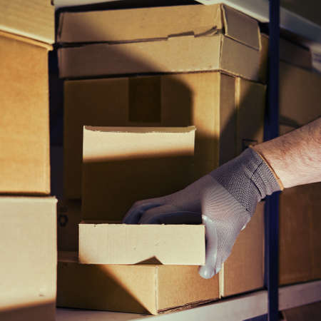 A man in gloves steals goods from a box in a warehouse. Problems with theft and security in the officeの写真素材