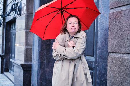 A woman with an umbrella freezes alone at the door of the house