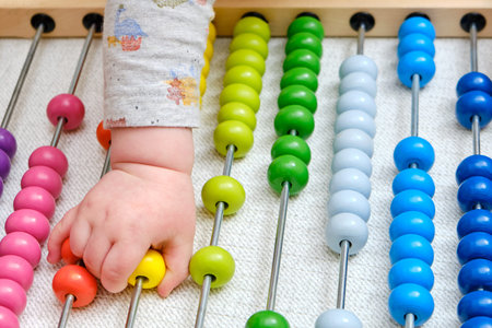 Toddler baby boy plays with his hands with colorful abacus on the floor, child with a toy in rainbow...
