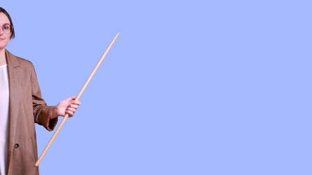 Smiling female teacher pointing to the side on studio blue background, banner copy spaceの写真素材